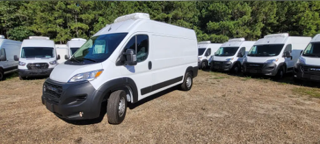 Refrigerated van with rooftop cooling unit parked in lot.