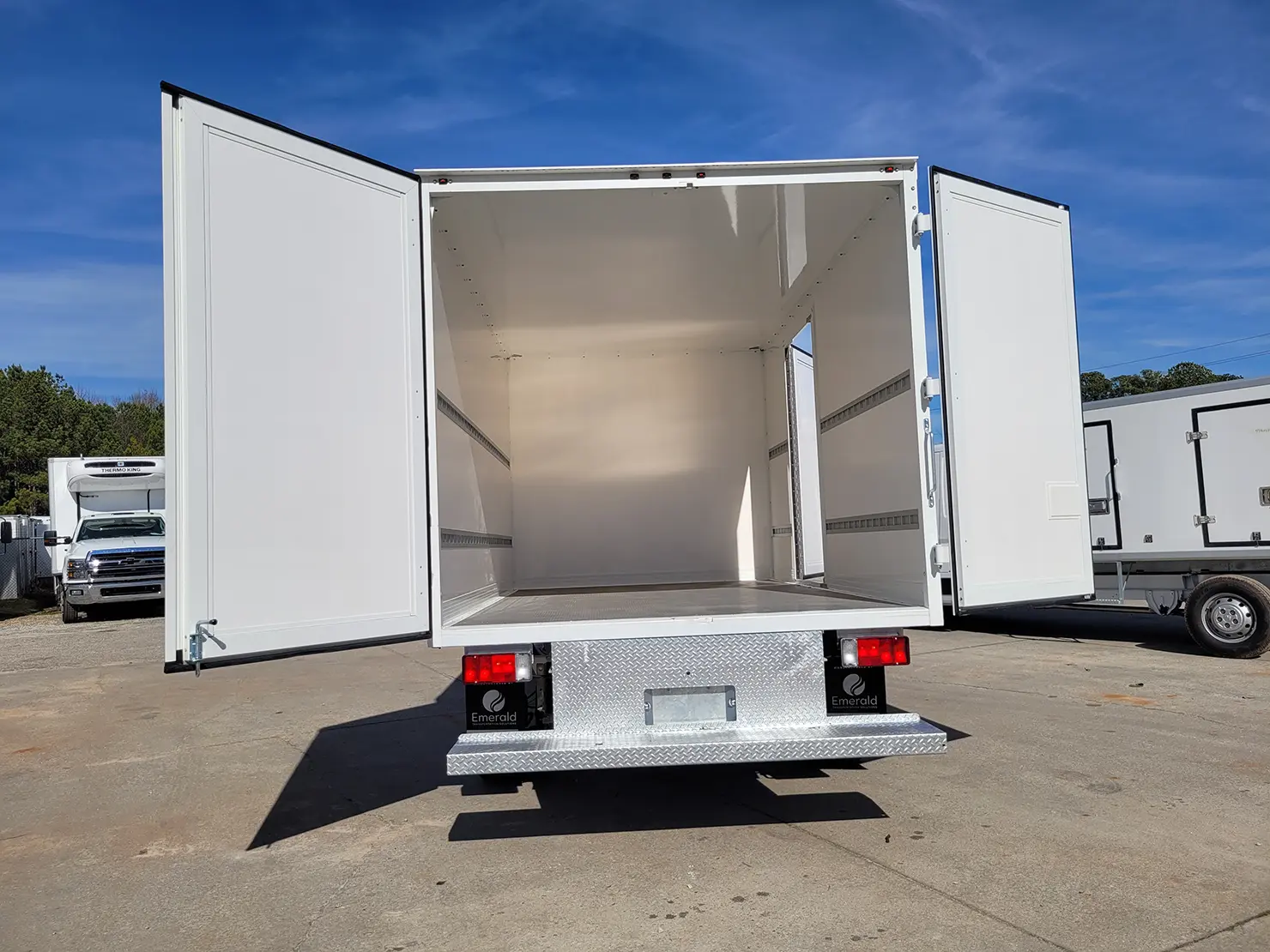 Rear view of an Emerald refrigerated box truck with open swing doors for full cargo access.