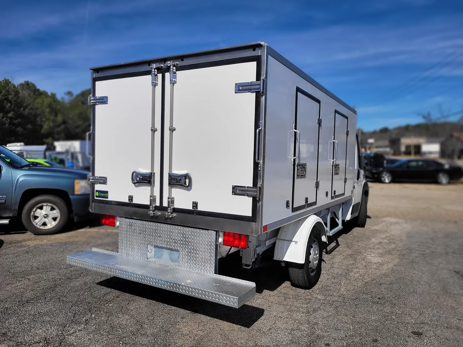 Rear view of an Emerald refrigerated truck featuring a full-width galvanized drop step bumper for easy cargo access.