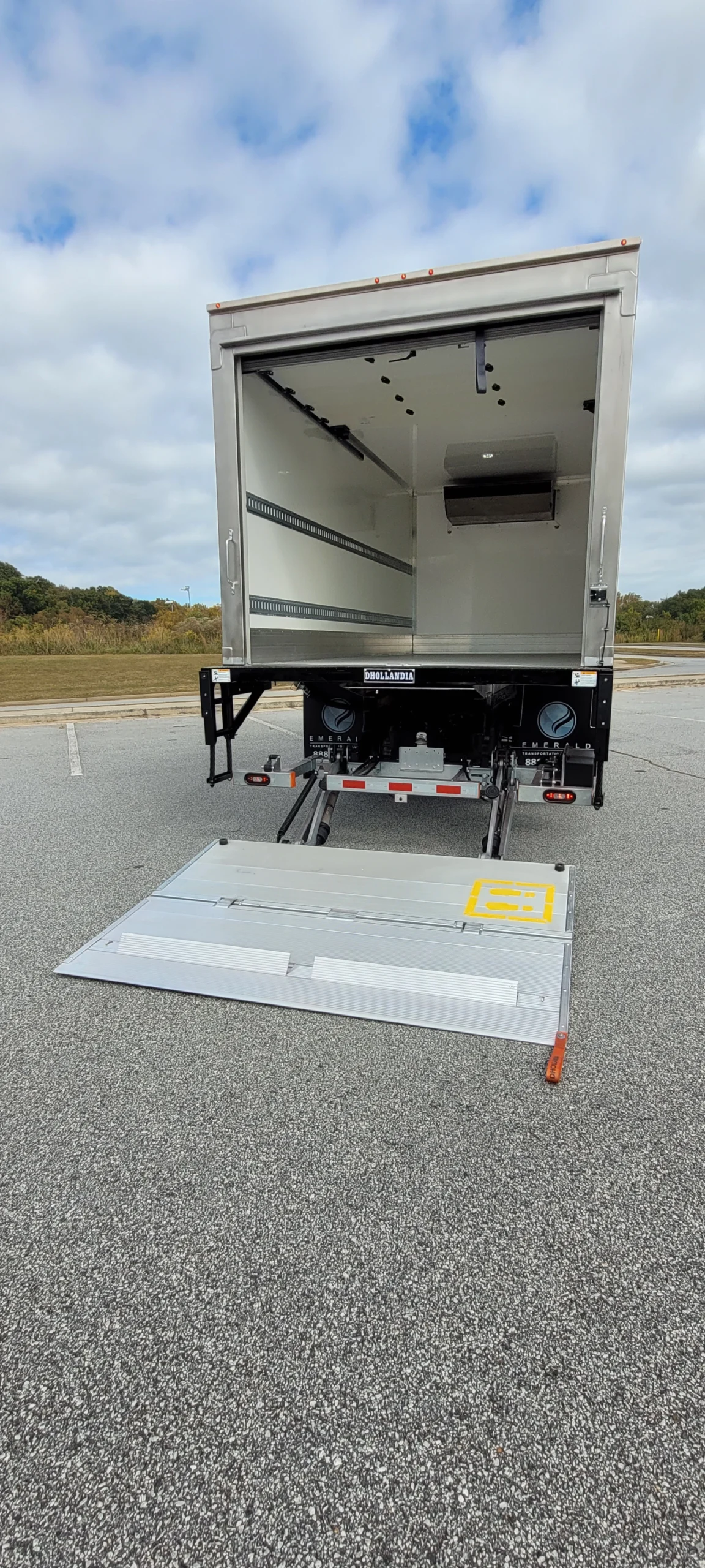 Rear view of an Emerald refrigerated truck with an extended hydraulic liftgate for loading and unloading heavy cargo.