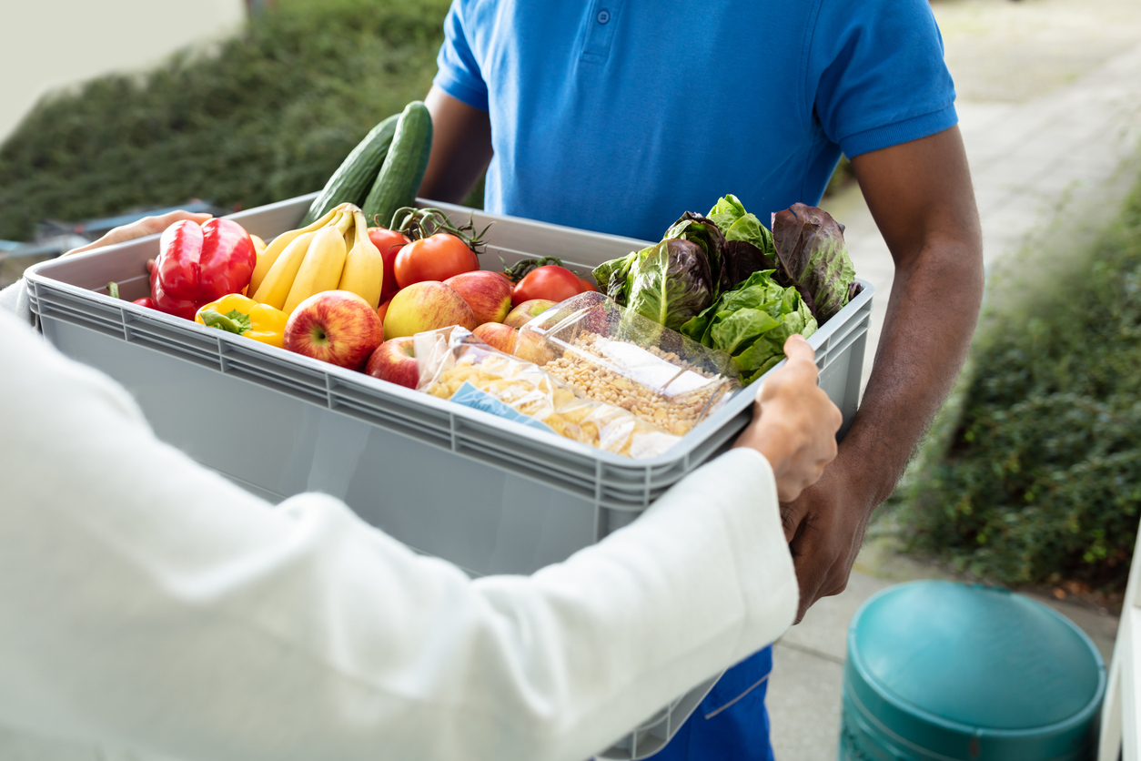 Smiling woman receiving nonprofit grocery delivery at home.
